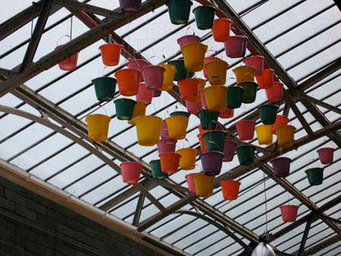 multicloured sprayed buckets hanging from glass ceiling of an old arm drill hall